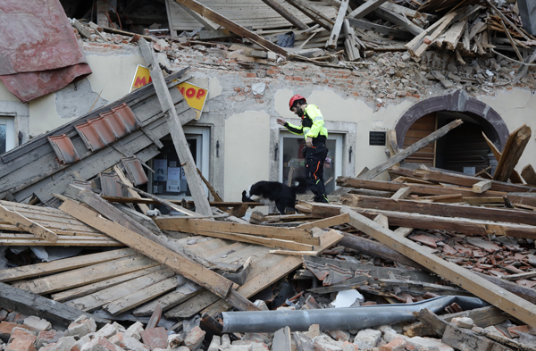 搜救人员带着一只嗅探犬进入废墟展开搜救工作。（欧新社）