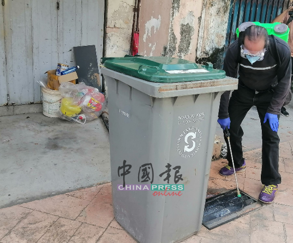 消灭孑孓队的义务人员在豆腐街的排水沟喷药水。