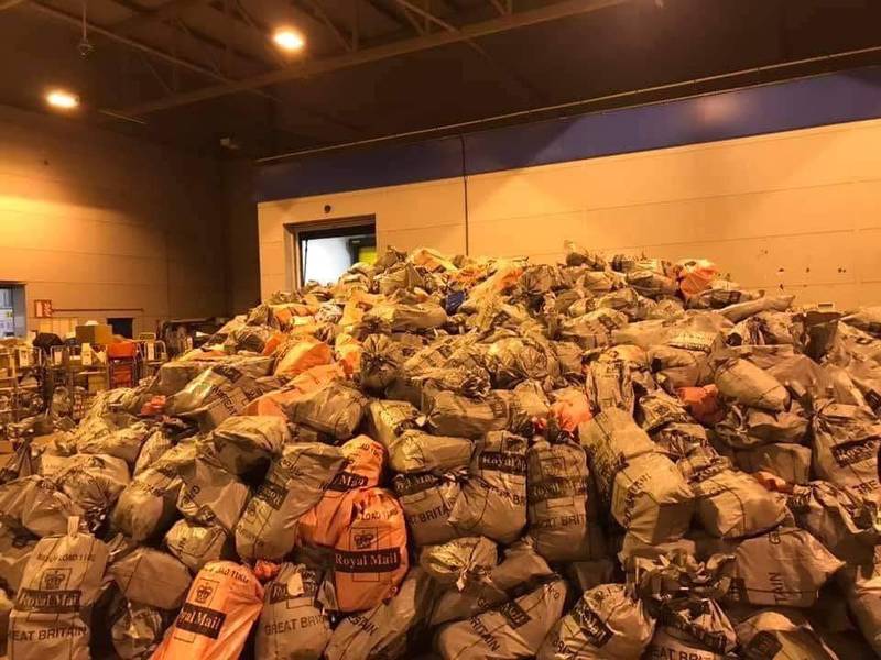 英国皇家邮政目前面临包裹爆量的窘境，高耸的包裹山堆放在各个分部。（互联网）