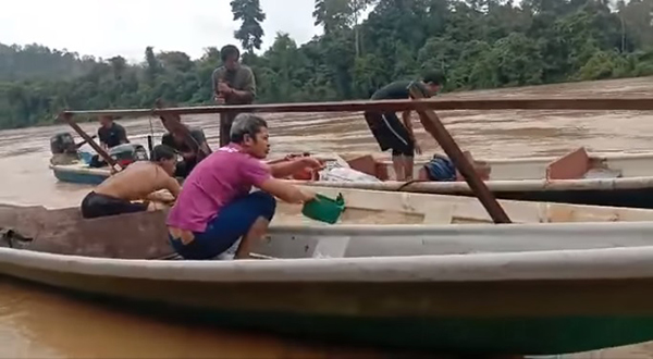 热心的甘榜班达村民合力把快艇内的水扫出外。