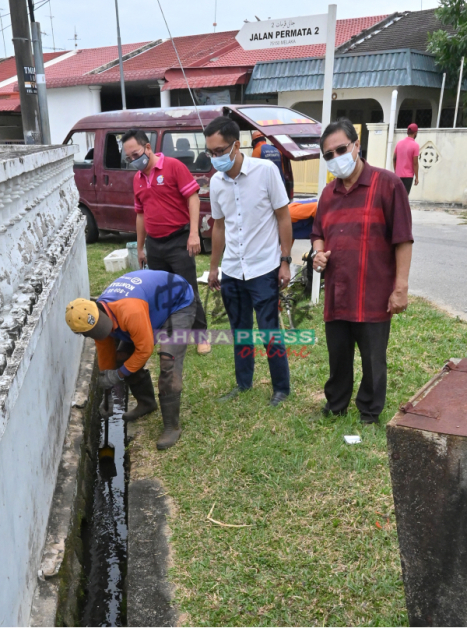 再诺（右起）、李翰霖及叶汉良看着员工清理沟渠的沉淀物。