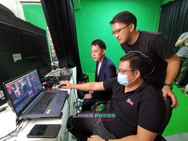 梁恩来（站者）与专业录影师刘铭亮，洽商线上婚礼细节，确保每个环节能顺利进行。