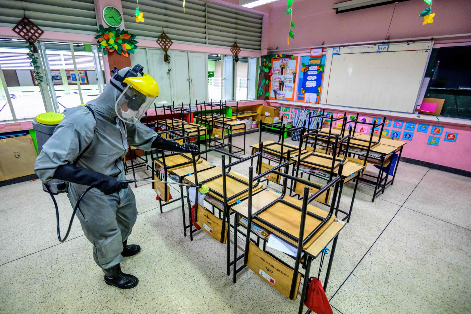 泰国2月1日开学复课，一名军人周四穿着防护服到曼谷学校消毒。
