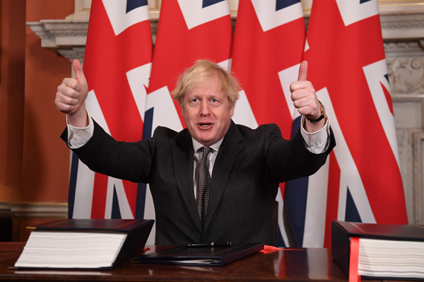 约翰逊周三在唐宁街10号签署英国脱欧后与欧盟的双边贸易协议，双手举起拇指比赞。（法新社）