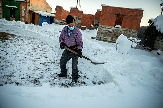 一名男子在屋外铲除积雪。（美联社）