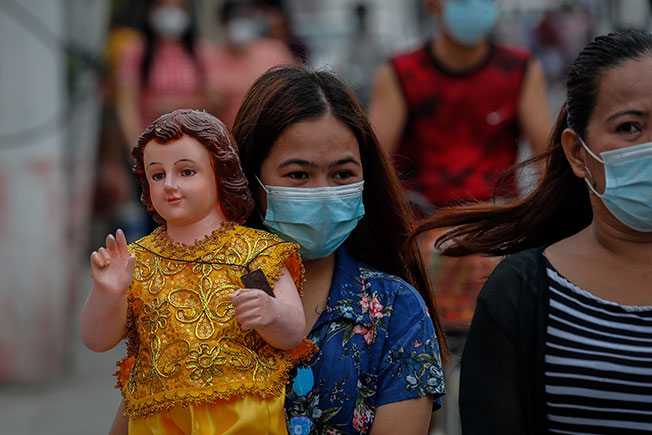 菲律宾邦板牙省一名女子周日出席圣婴节礼拜后，捧着圣婴像行走。（欧新社）