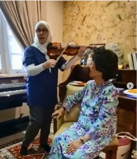东姑阿兹札（左）边拉小提琴，变扮出陶醉模样，逗得一旁的西蒂哈丝玛哈哈大笑。