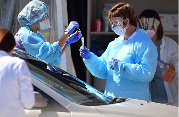 美国医护人员在检测车道上为民众进行新冠肺炎检测。