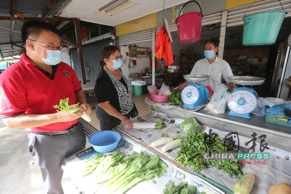 李殿成（左起）及刘运珍询问新村内卖菜业者的生意。