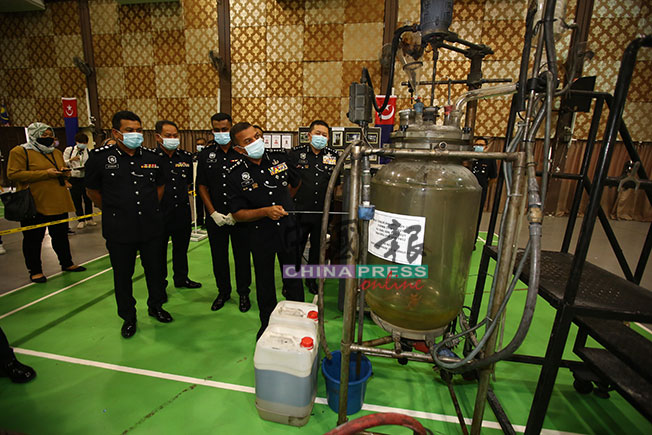 阿育甘（前排右）指工厂内放置大型炼毒工具。
