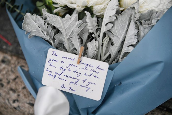 亲友在车祸现场放置鲜花及卡片，字里行间表达对死者们的思念。（海峡时报）