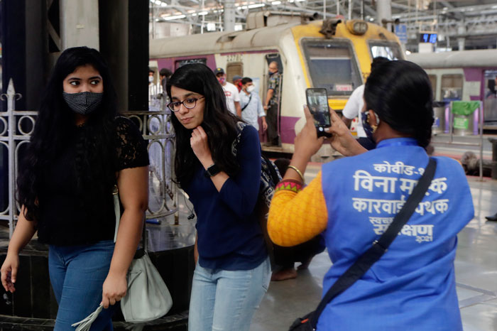 孟买市政局人员用手拍下没有戴口罩的民众。（美联社）