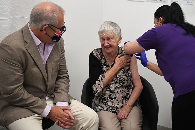 养老院居民马利西亚克（中）是澳洲首位接种新冠肺炎疫苗的人，莫里森（左）全程陪伴她。（美联社）