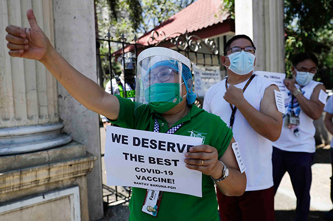 菲律宾一名戴口罩和面罩的医护人员，周六在马尼拉的中央医院外示威，呼吁政府给予医护人员最安全、最高功效和效力的疫苗。菲律宾预料将在周末接到中国科兴疫苗，但医护人员却反对接种中国科兴疫苗。（美联社）