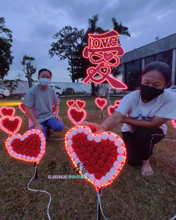 钟宛吟（右）展示“爱铺满地”的“心”，都是用瓶盖制作。左为方莉霞。