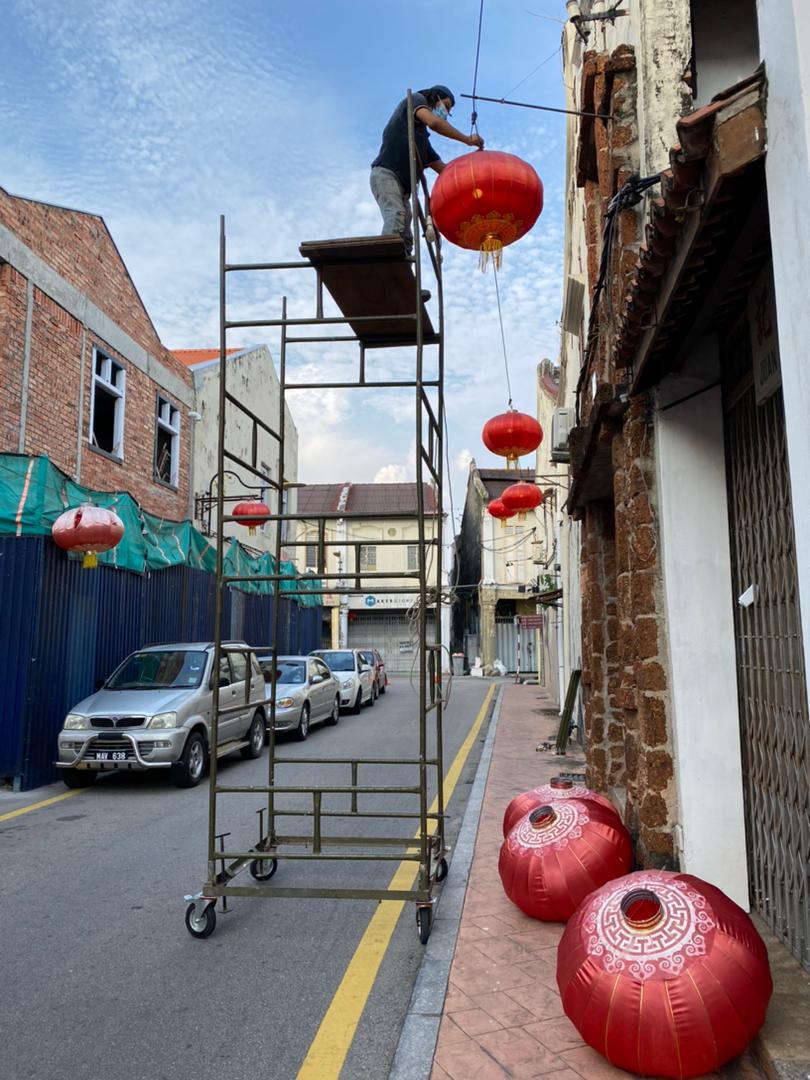 林善初联同数位友人在年二八更换豆腐街的灯笼，寓意迎新送旧。