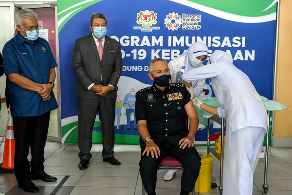 韩查再努丁（左）巡视内政部高官接种疫苗情况，接种疫苗者是副警察总长阿克里沙尼，中间者为旺阿末达兰。（马新社）