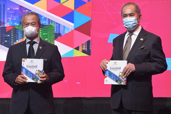 慕尤丁（左）推介2021-2025年马来西亚合作社转型大蓝图；右为旺朱乃迪。