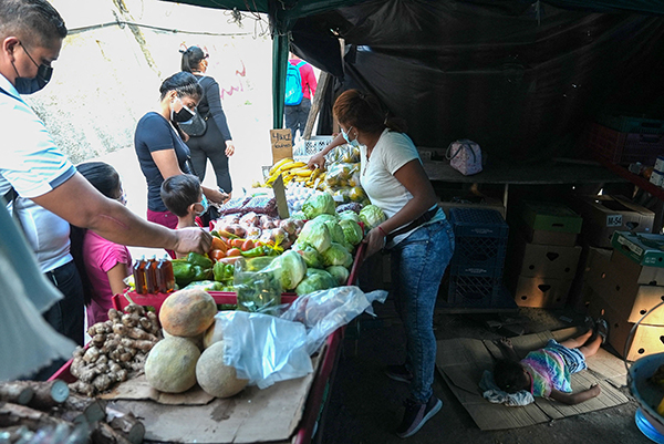 巴拿马市郊的埃里卡在街头小摊工作，3岁女儿约瑟琳在摊子后方地面睡觉。（法新社）