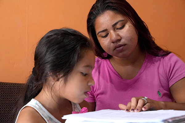 母亲孟多萨协助8岁女儿布瑞塔妮在家学习。（法新社）