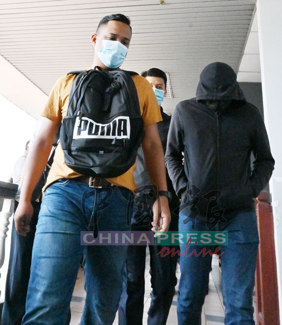 穿着深灰色外套遮脸的卡尔云德吉星（右），被押离法庭时，被同行以肉体阻挡，避免记者拍摄。