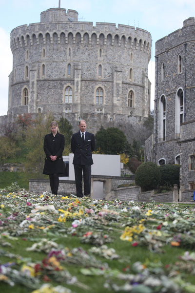 威塞克斯伯爵爱德华王子和女儿路易丝·温莎女爵，周五在温莎堡外望着民众献给菲利普亲王的献花，缅怀追思。（法新社）
