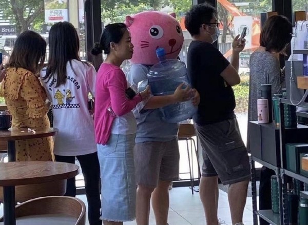 星巴克自带杯限时免费活动，有人戴上粉色猫脸卡通头套，手里捧着桶装水的空桶排队。