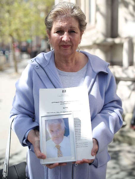 带着冤屈离世的前邮政局局长威尔逊的遗孀卡伦，在法庭外手持亡夫照片，