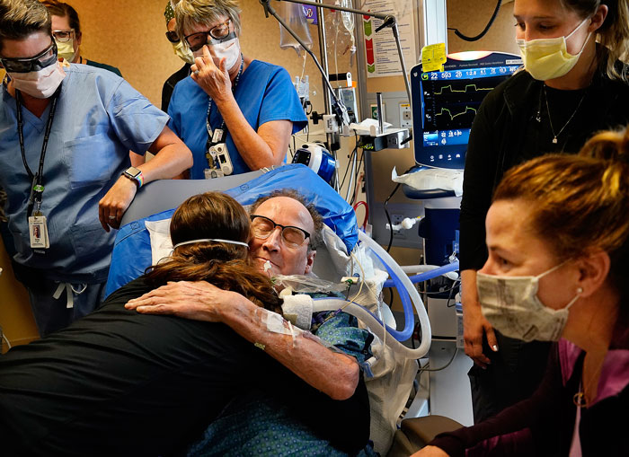 美国明尼阿波利斯一名病重新冠肺炎患者，在接受81天治疗后周一终于获准出院，他在病床上与医护人员拥抱道别。（美联社）