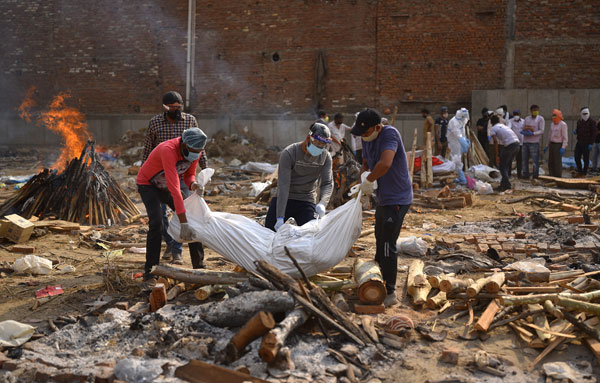 在新德里一个火化场，工作人员将新冠死者的遗体进行火化。（欧新社）