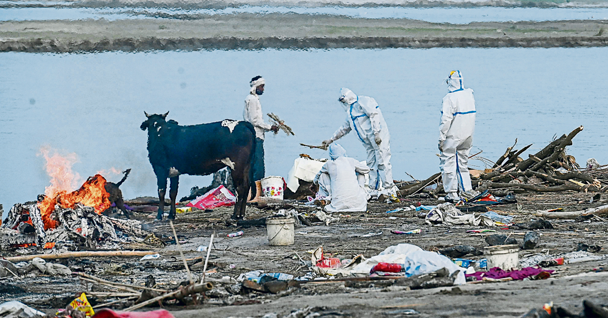 印度北方州哈普尔区加尔赫穆克泰斯赫瓦尔村,周三有家属身穿防护装备,在恒河岸边火化疫殁者遗体。(法新社)