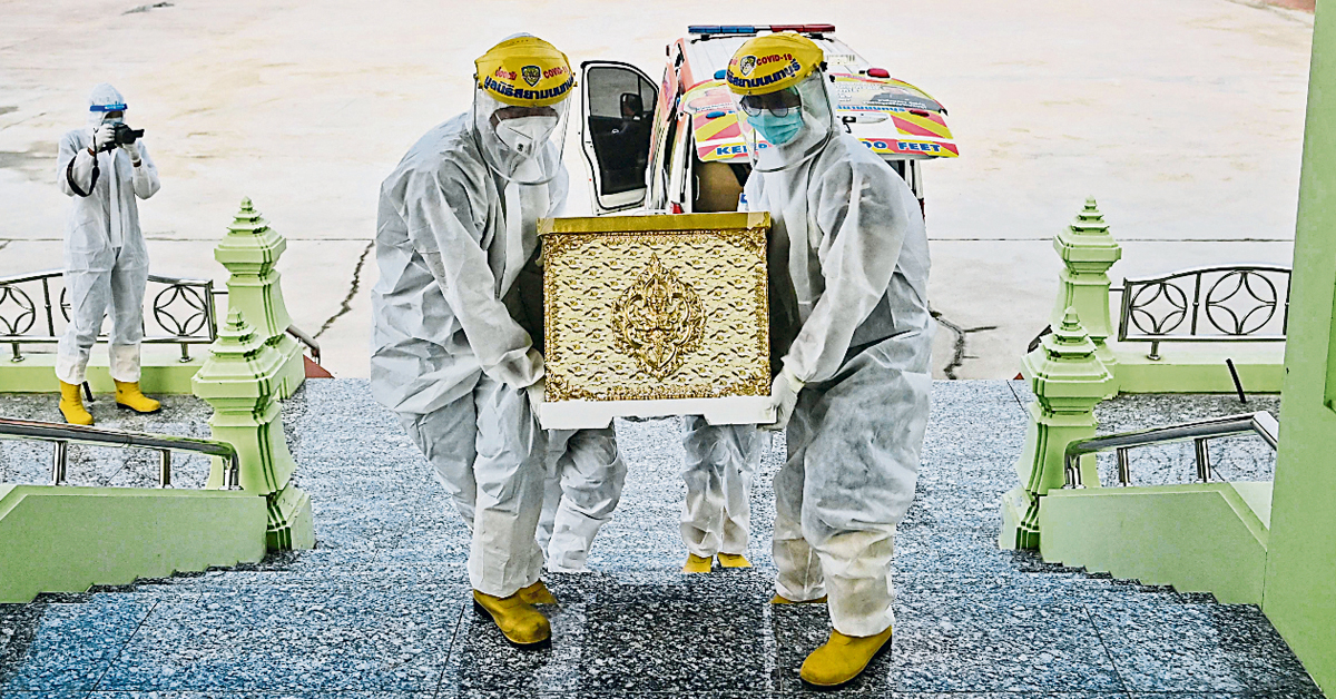 泰国暖武里府的慈善机构义工,周三将一名女患者遗体,送入拉特普拉空潭佛寺进行火化。(法新社)