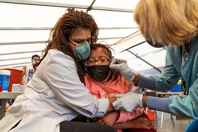 周六在洛杉矶，2名医护人员为一名患有唐氏综合症的17岁少女接种辉瑞疫苗后，给她拥抱安抚。（美联社）