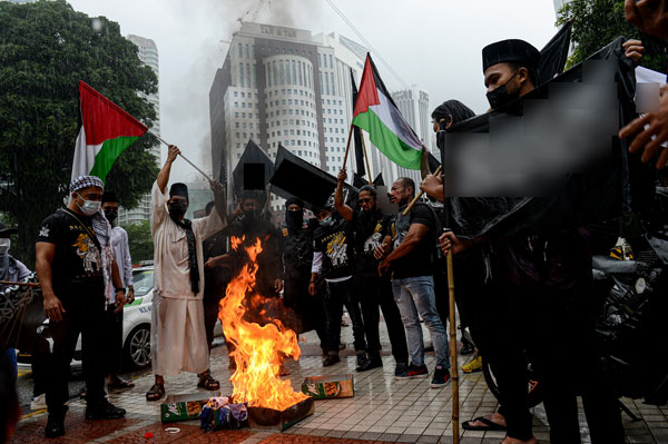 非政府组织成员聚集在大使馆外，祈祷及声援巴勒斯坦，同时在现场焚烧物件。（马新社）