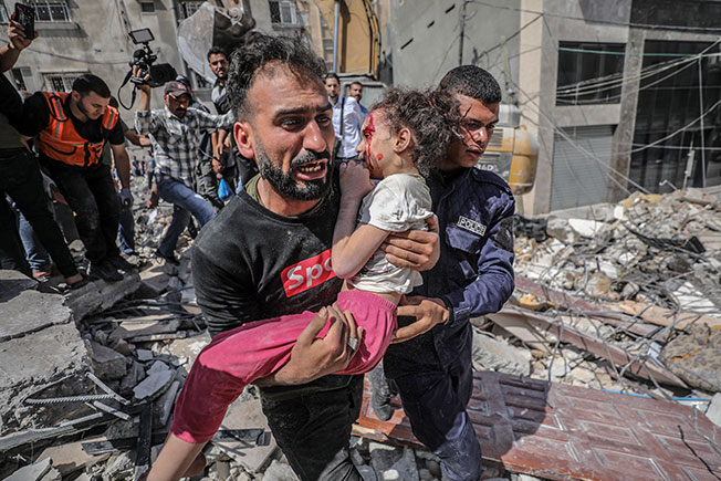 一名巴勒斯坦父亲，周日从被炸毁的房屋里抱出受伤的女儿。（欧新社）