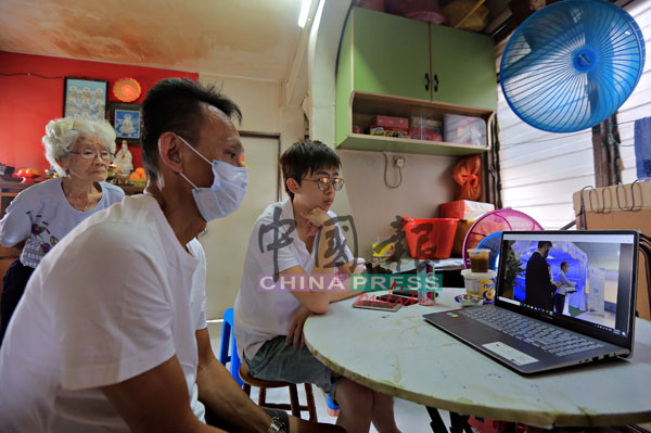 葉子成（左）與兒子葉毅樂，通過手提電腦連線觀看出殯全程，遠距離目送至親最後一程，站者為黃麗娟。