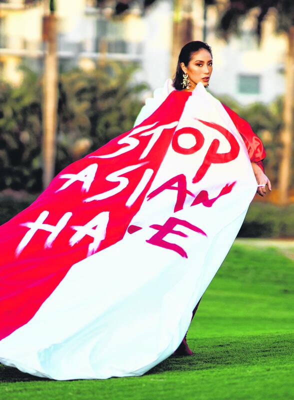 红白两个底色的披风上用类似喷漆字体写着“停止仇视亚裔”（Stop Asian Hate）的字样。（新加坡环球小姐）