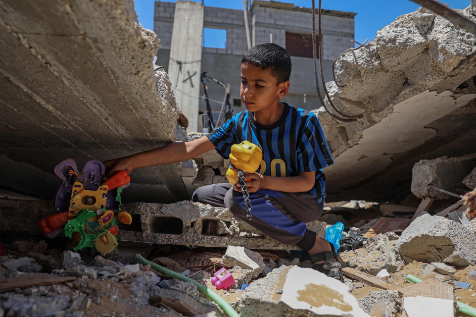 加萨一名男童在被炸毁的住家废墟中寻回玩具。（法新社）