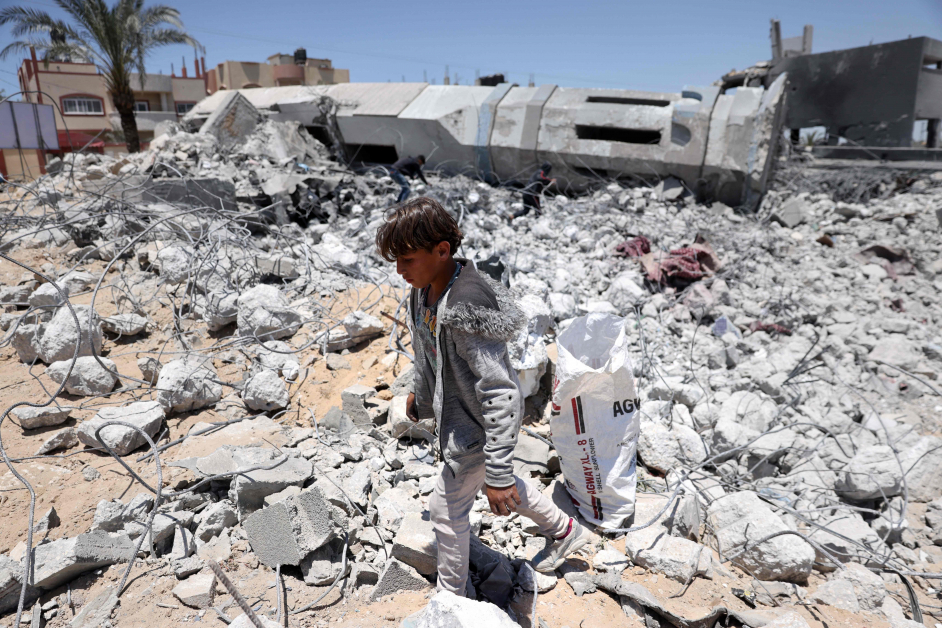 一名巴勒斯坦少男在加萨北部拜特拉希亚一座被摧毁的清真寺废墟中收集碎片。（法新社）
