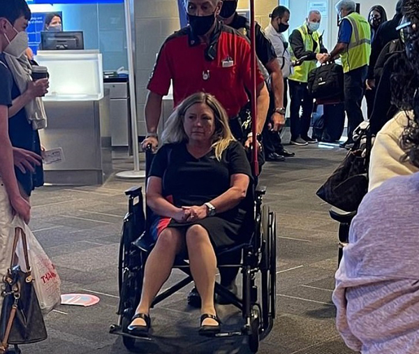 飞机着陆后，受伤的空姐坐轮椅离开机场接受治疗。