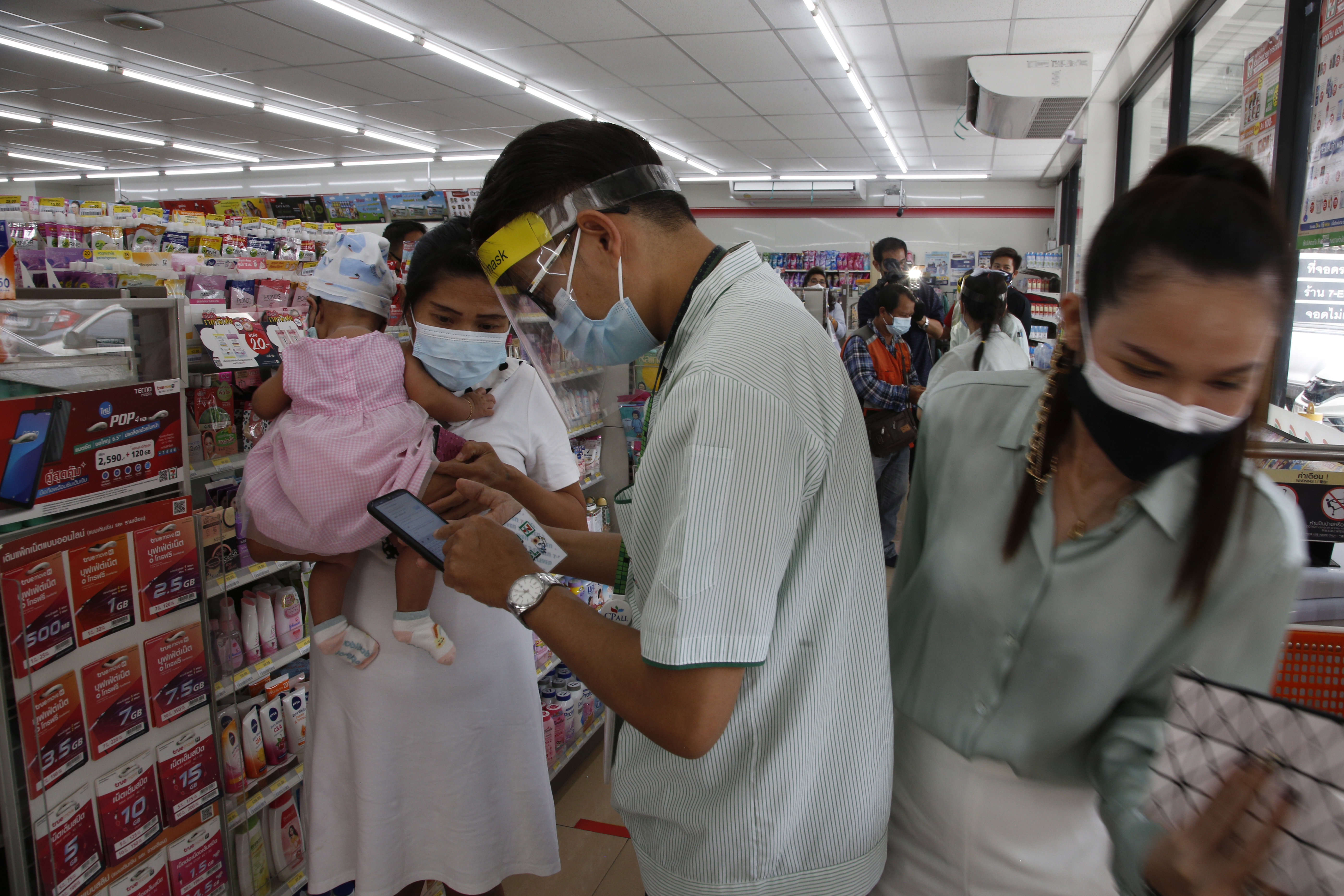 泰国曼谷便利店的工作人员，周四在店里帮一名抱着婴儿的妇女登记接种疫苗。当天起，曼谷18至59岁民众可以在3300多家便利店中进行登记注册，并将于6月7日将开始接种疫苗。（欧新社）