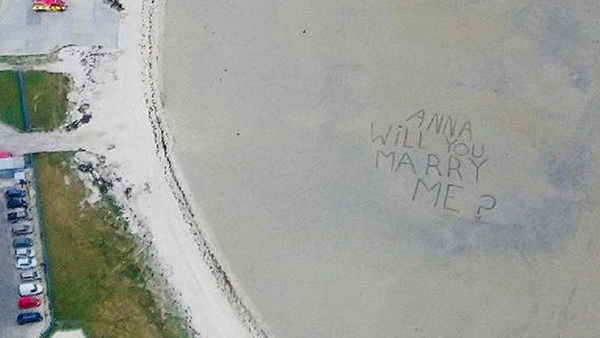 海滩上写着“安娜，你愿意嫁给我吗？”。
