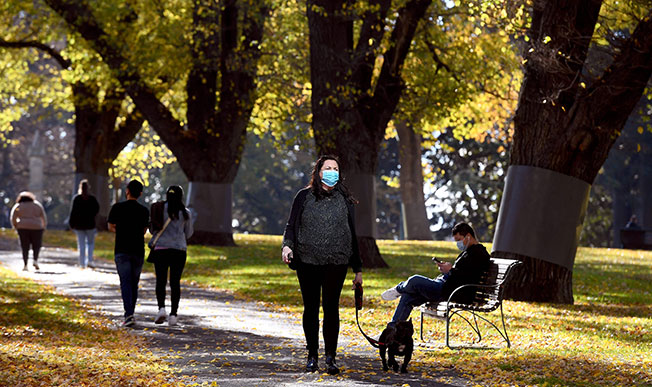 澳洲民众周四在墨尔本市内公园散步时戴口罩。（法新社）