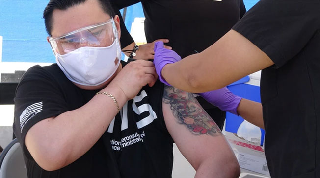 美国疫苗普及供应充裕，各地出现“疫苗观光”刺激经济。图为墨西哥旅客在洛杉矶机场施打免费疫苗。