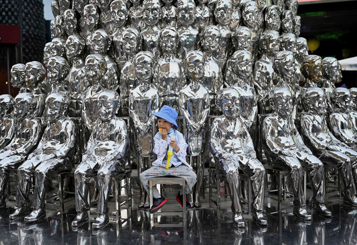 6月1日是国际儿童节，北京一名小男孩当日在一家购物商场内的孩童雕塑前合照。（法新社）