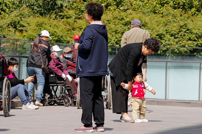 北京一名老妇5月10日在一栋办公大楼外，跟孙玩耍。（美联社）
