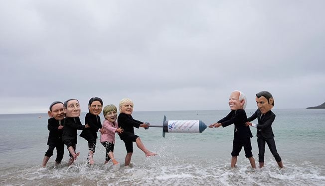 乐施会活动分子周六装成G7的形象，在斯旺普海滩争夺一支巨大“疫苗”。（美联社）