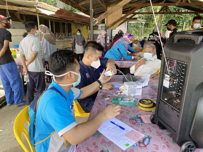 接种疫苗前，医护员为村民检查健康，测量血压。