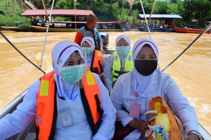医护员冒着性命危险，乘船为偏远甘榜村民注射冠病疫苗。