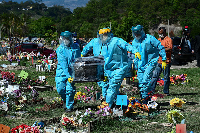 周日在洪都拉斯首都特古西加尔巴，殡葬人员准备埋葬一名新冠死者的遗体。（法新社）